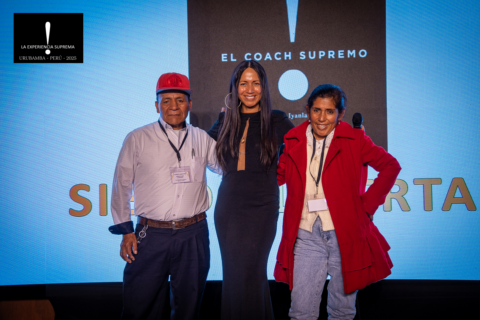 Gaby Puma standing with her mother and father on stage at La Experiencia Suprema 2025 in Urubamba, Peru, celebrating leadership and family.